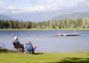 Retired couple looking over a beautiful lake with mountains in the background