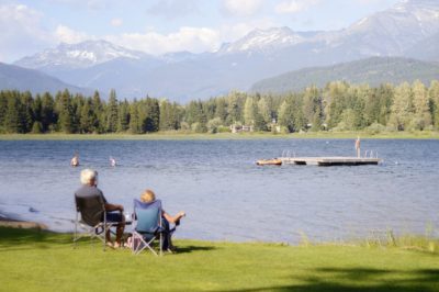 Retired couple looking over a beautiful lake with mountains in the background